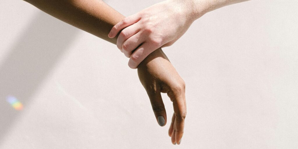 Two people of different ethnic backgrounds holding hands, symbolizing unity and support.